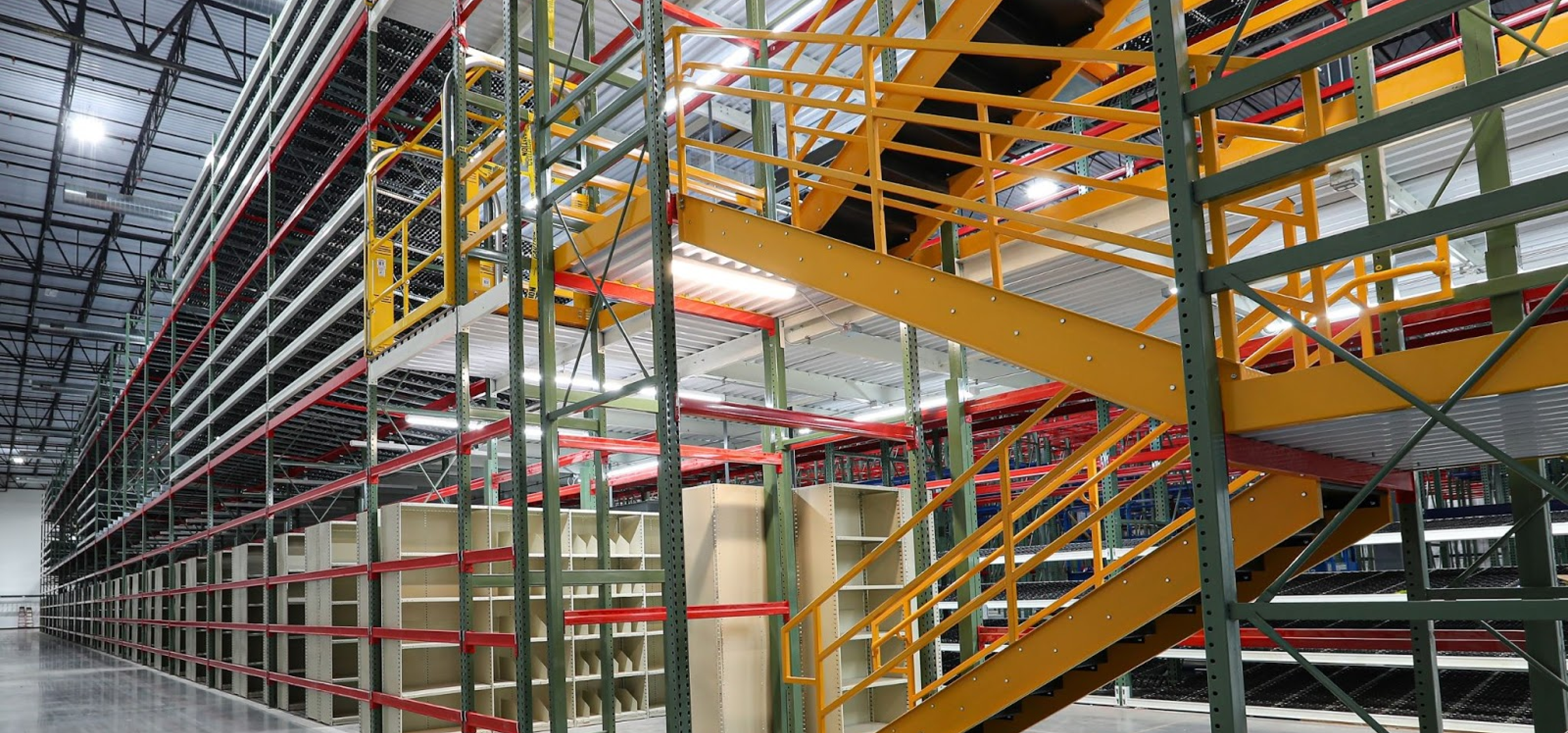 Apex Companies warehouse mezzanine installation with multi-level shelving and yellow staircase